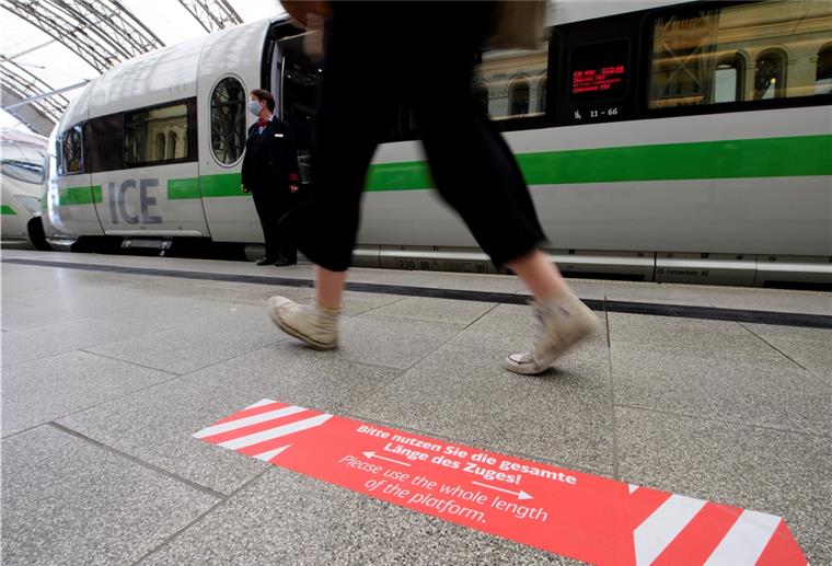 Ein Aufkleber mit der Aufschrift „Bitte nutzen Sie die gesamte Länge des Zuges!“ ist auf einem Bahnsteig vor einem haltenden ICE zu sehen.