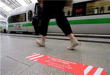 Ein Aufkleber mit der Aufschrift „Bitte nutzen Sie die gesamte Länge des Zuges!“ ist auf einem Bahnsteig vor einem haltenden ICE zu sehen.