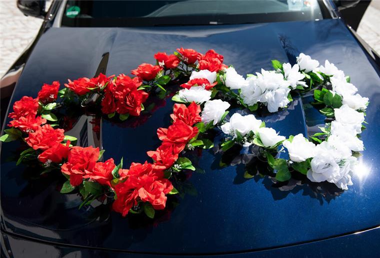 Blumenschmuck ist auf dem Auto des Hochzeitspaars befestigt.