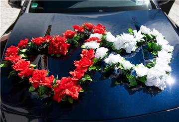 Blumenschmuck ist auf dem Auto des Hochzeitspaars befestigt.
