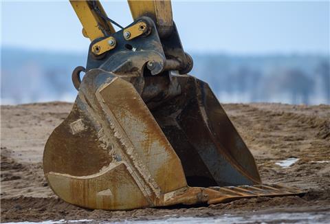 Die Schaufel eines parkenden Baggers ruht auf der Baustelle am Boden der Autobahn 14 (A14). 