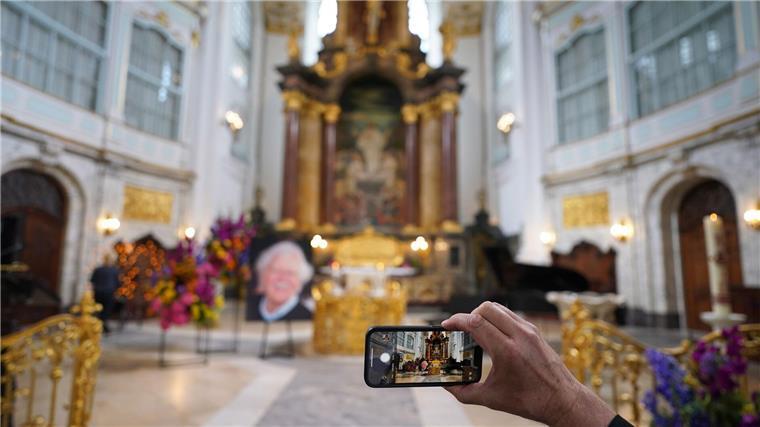 Ein Besucher macht zu Beginn der Trauerfeier ein Foto mit einem Smartphone.