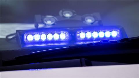 Ein Blaulicht leuchtet unter der Frontscheibe eines Einsatzfahrzeugs der Polizei.