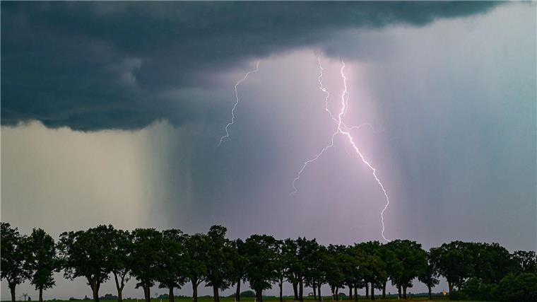 Ein Blitz leuchtet am späten Abend über der Landschaft.