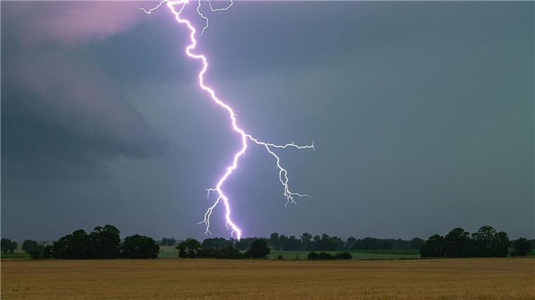 Ein Blitz leuchtet über einer Landschaft auf.