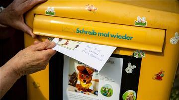 Ein Brief, den ein Kind für den Osterhasen geschrieben hat, wird in einen Briefkasten geworfen.