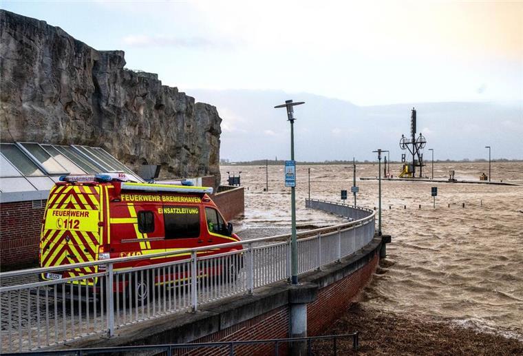 Ein Einsatzfahrzeug der Feuerwehr steht bei Sturmflut am Ufer der Wesermündung in Bremerhaven.