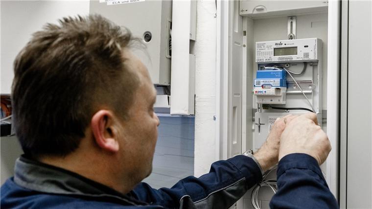 Ein Elektriker montiert einen digitalen Stromzähler mit einem Smart-Meter-Gateway zur Datenübertragung.