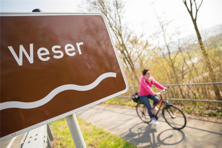 Weser-Radweg ist der beliebteste in Deutschland Ein Fahrradfahrer fährt auf dem Weser-Radweg vorbei an einem Wegweiser, an dem unter anderem ein Schild mit der Aufschrift "Weser".