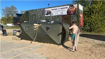 Ein Festival-Besucher steht vor einer mobilen Front-Sauna, die in Estland für die ukrainische Armee entwickelt worden ist.