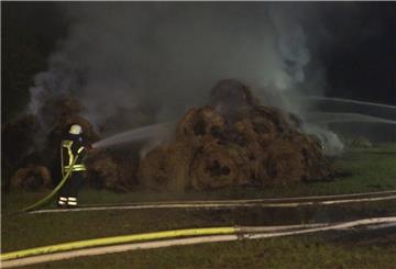 Ein Feuerwehrmann löscht brennende Strohballen.