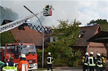 Ein Feuerwehrmann öffnet von der Drehleiter aus das Dach, um die Flammen bekämpfen zu können.