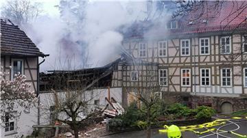 Ein Feuerwehrmann steht bei Löscharbeiten in der Nähe von den Klinik Gebäuden.