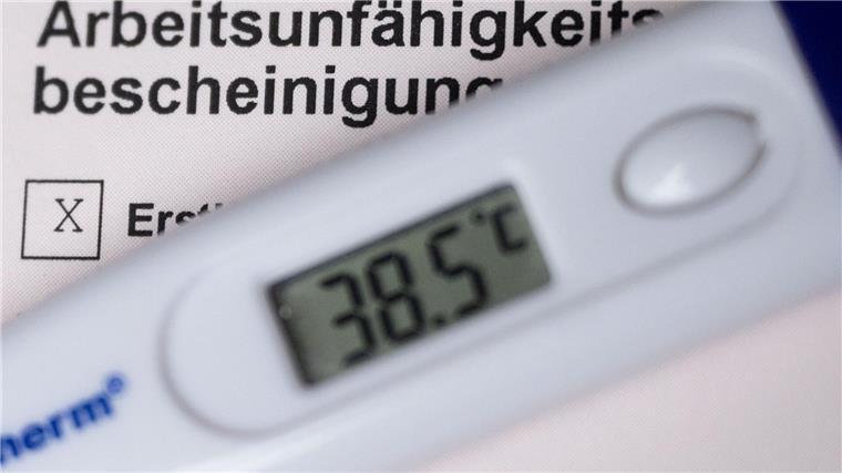 Ein Fieberthermometer liegt auf einer Arbeitsunfähigkeitsbescheinigung.