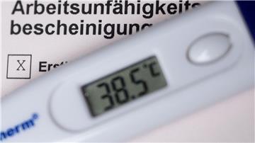 Ein Fieberthermometer liegt auf einer Arbeitsunfähigkeitsbescheinigung.