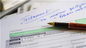 Ein Formular für die Erbschaftsteuererklärung sowie Stift und Testament liegen auf einem Tisch.