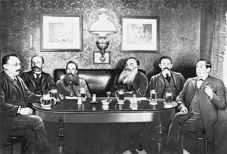 Sechs Männer sitzen an einem Tisch und trinken Bier