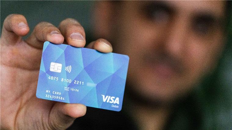 Ein Geflüchteter hält eine Debitcard in der Hand.