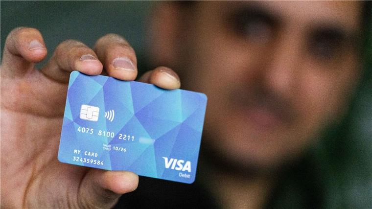 Ein Geflüchteter hält eine Debitcard in der Hand.