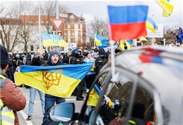 Ein Gegendemonstrant trägt eine ukrainische Flagge und stellt sich einem Auto des prorussischen Auto-Korsos in Hannover entgegen.
