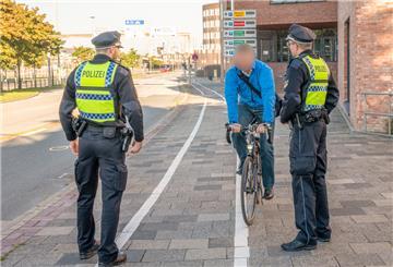 Zwei Polizisten stehen auf der Columbusstraße/Kennedybrücke in Bremerhaven und halten einen Radfahrer an.
