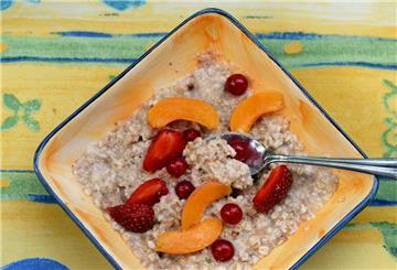 Eine Schale mit Porridge und Obst steht auf einem Frühstückstisch.
