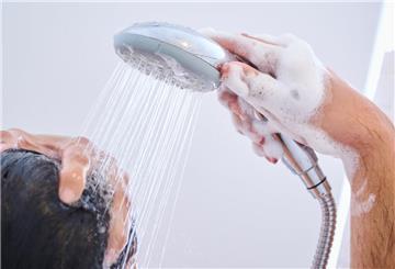 Ein Mann wäscht sich unter der Dusche die Haare.