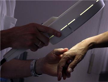 Ein Hautarzt untersucht mit einem Vergrößerungsglas eine Patientin.