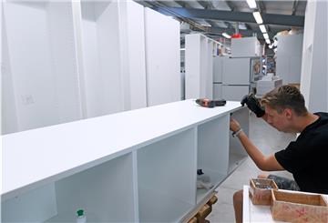 Ein Holzmechaniker montiert in einer Möbelbaufirma Schränke. Mittlererweise ist aber Holz zum knappen Rohstoff geworden, wodurch es zu Engpässen kommt.