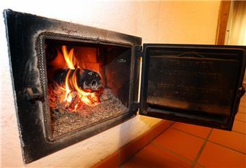 Ein Holzofen wird vom Hausflur aus mit Holzbriketts geheizt