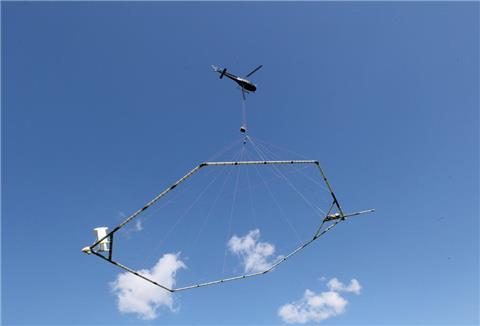 Ein Hubschrauber schleppt eine Antenne über den Grund, die nach dem SkyTEM-Verfahren den Aufbau des Untergrundes misst.
