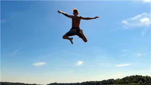 Ein Junge springt in das Wasser eines Sees.