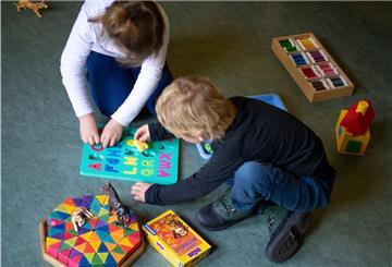 Ein Junge und ein Mädchen spielen in einem Kindergarten auf dem Boden. 