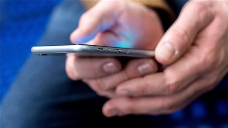 Ein junger Mann sitzt in einer S-Bahn und benutzt dabei sein Smartphone.