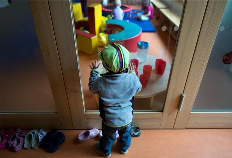 Hepstedt: Eltern wünschen sich Kinderbetreuung Ein Kleinkind steht an einer Glasscheibe in einer Kindertagesstätte und schaut anderen Kindern beim Spielen zu. Wegen der Pandemie laufen die Kitas nur im Notbetrieb. Normalität wünschen sich auch in Hepstedt immer mehr Eltern und Kinder.