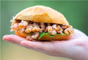 Ein Krabbenbrötchen liegt in einer Hand.
