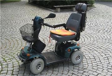 Ein Krankenfahrstuhl steht auf einem Kopfsteinpflaster.