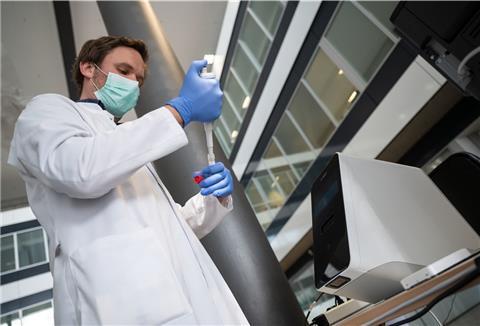 Ein Labor-Mitarbeiter entnimmt im Robert-Bosch-Krankenhaus (RBK) in Stuttgart eine Testflüssigkeit für einen Coronavirus-Schnelltest.