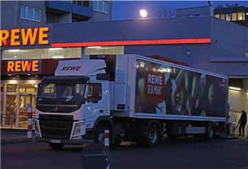 Ein Lkw steht am frühen Morgen vor einem Rewe-Supermarkt, der mit Waren beliefert wird.