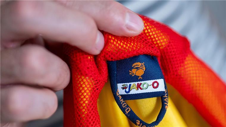Ein Mann hält eine Kinderjacke der Modemarke Jako-o in der Hand.