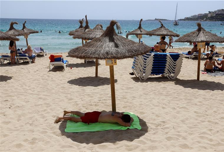 Corona: Spanien zum Riskogebiet erklärt Ein Mann liegt unter einem Sonnenschirm am Strand von Cala Major in Palma de Mallorca.