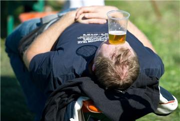 Ein Mann pausiert mit einem Bierbecher auf der Stirn. Männer haben Probleme damit, den Erwartungen zu entsprechen, die heutzutage an sie gerichtet werden.