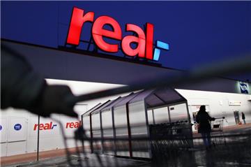 Ein Mann schiebt seinen Einkaufswagen vor einem Real-Markt.