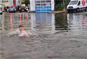 Ein Mann schwimmt auf einer überschwemmten Straße in Braunschweig und sorgt für gute Laune bei den umstehenden Passanten.
