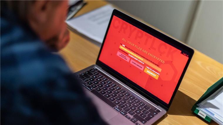 Internetuser sehen sich von Cyberkriminalität bedroht Ein Mann sitzt vor einem Laptop, der mit einem Verschlüsselungstrojaner (Ransomware) befallen ist.