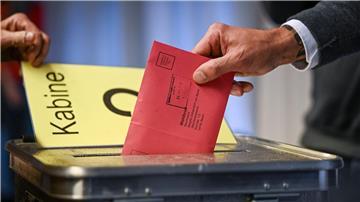 Ein Mann steckt seine Stimmzettel in einem Briefumschlag in die Wahlurne.
