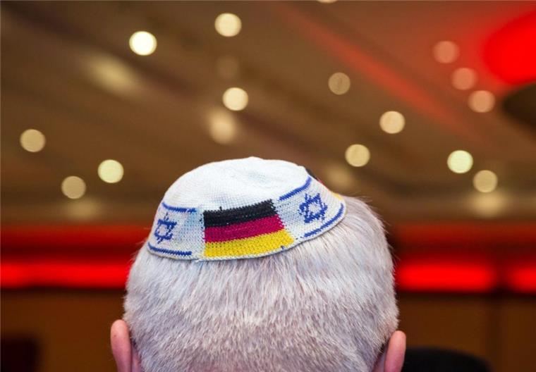 Ein Mann trägt eine Kippa mit eingearbeiteten israelischen und deutschen Fahnen. 