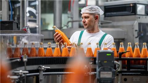 Ein Mitarbeiter der Firma Voelkel kontrolliert Glasflaschen nach dem Abfüllen.
