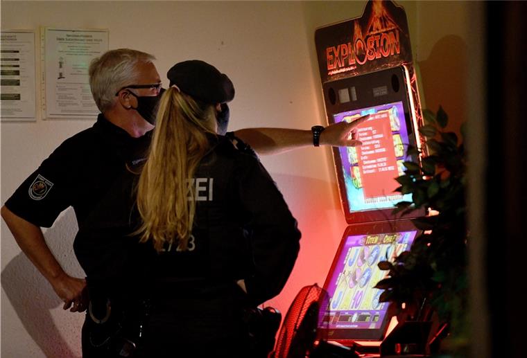 Ein Mitarbeiter des Ordnungsamtes und eine Polizistin sehen sich in Essen während einer Razzia einen Spielautomaten an.
