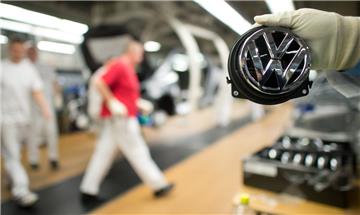 Ein Mitarbeiter hält  ein Volkswagen-Logo im VW-Werk in Wolfsburg (Niedersachsen) an der Produktionsstraße für den VW Golf VII. 